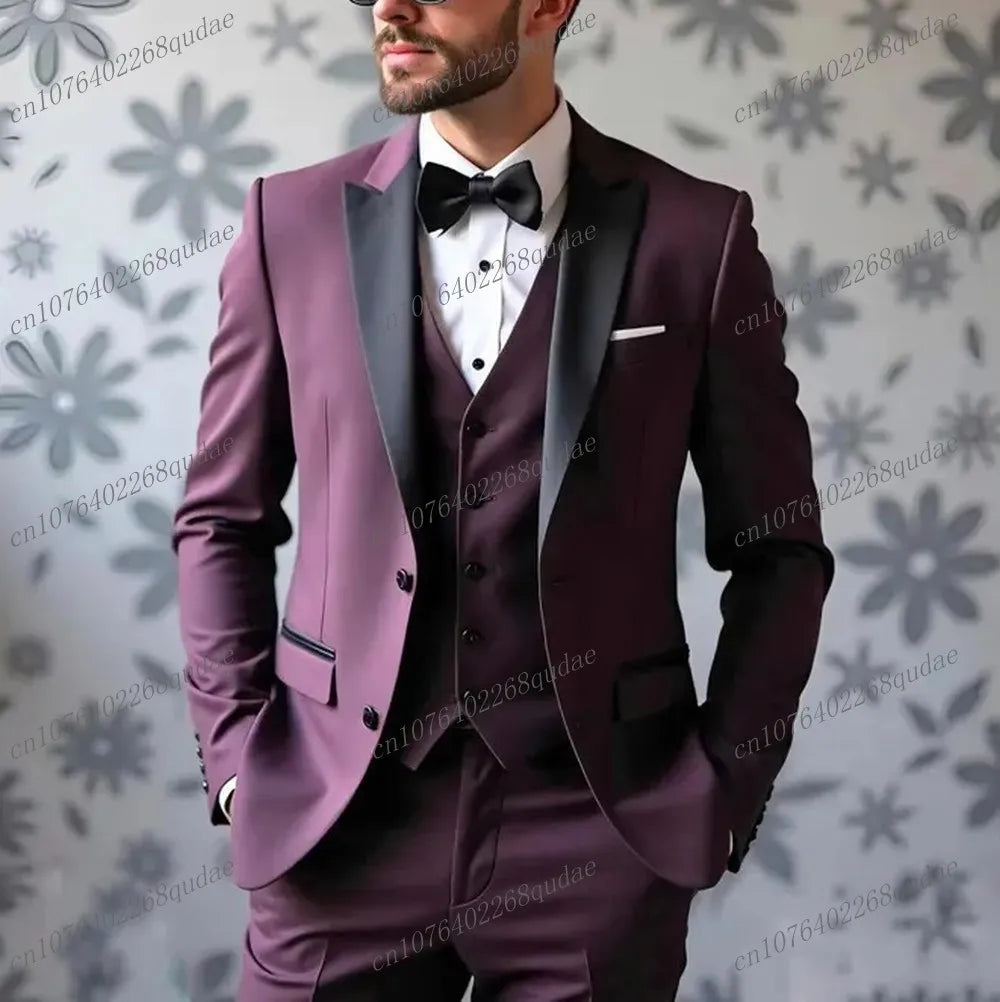 A man wears a three-piece burgundy suit with a black shawl collar, vest, and matching bow tie.