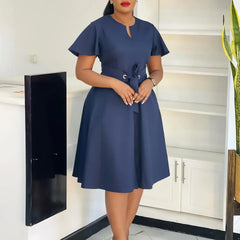 A woman wears a navy blue knee-length A-line dress with short sleeves and a waist tie.