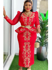A woman wears a red long-sleeved dress with gold embroidery, a peplum waist, and a gold belt.