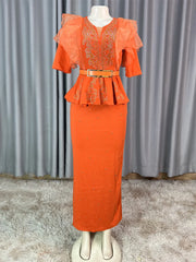 An orange ankle-length dress with a peplum waist, rhinestone embellishments, and ruffled sleeves.