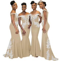 Four women wear matching tan off-the-shoulder mermaid bridesmaid dresses with white lace appliques.
