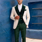 A man wears a three-piece formal suit featuring a white blazer with dark green lapels, a dark green vest, and matching dark green trousers.