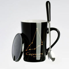 A black ceramic mug featuring a gold Capricorn constellation design, complete with a lid and spoon.