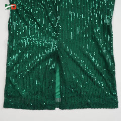 A close-up of a dark green sequined pencil dress featuring a vertical back slit.