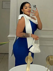 A woman wears a sleeveless, mid-length royal blue dress with a white bow detail at the shoulder.