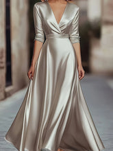 A floor-length champagne satin A-line gown with a V-neck and long sleeves.