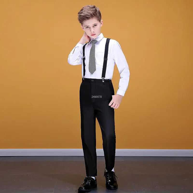 A boy wears a formal white dress shirt with a striped tie, black suspenders, and black trousers.
