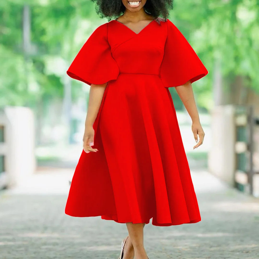 A woman wears a solid red, V-neck midi dress with butterfly sleeves and a pleated A-line skirt.