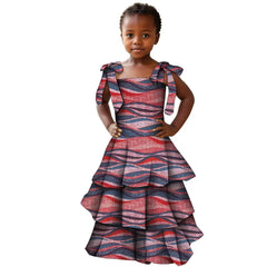 A young girl wears a tiered, sleeveless dress featuring a red and blue wavy African print pattern.