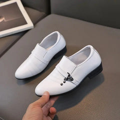A pair of white leather loafers for boys featuring a decorative metal buckle and low black heels.