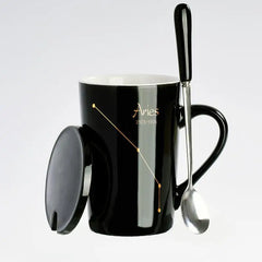 A black ceramic Aries zodiac mug with a matching lid and a long-handled spoon.