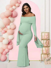 A pregnant woman wears a light green off-shoulder long-sleeve mermaid maternity dress.