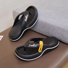 A pair of black platform flip-flops with a white stripe and a yellow smile tag on the strap.