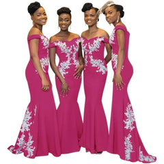 Four women wear matching off-the-shoulder burgundy mermaid dresses with white floral lace appliques.