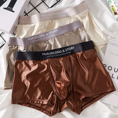 Three pairs of smooth, satin-like men's boxer shorts in cream, grey, and brown.