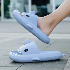 A pair of light blue shark-shaped slide sandals with teeth details on the front.