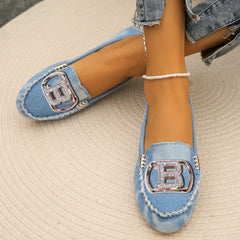 Light blue denim loafers featuring a prominent metallic B logo with rhinestone accents.