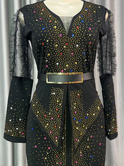 A black ankle-length dress with puff sleeves, a gold belt, and colorful diamond embellishments.