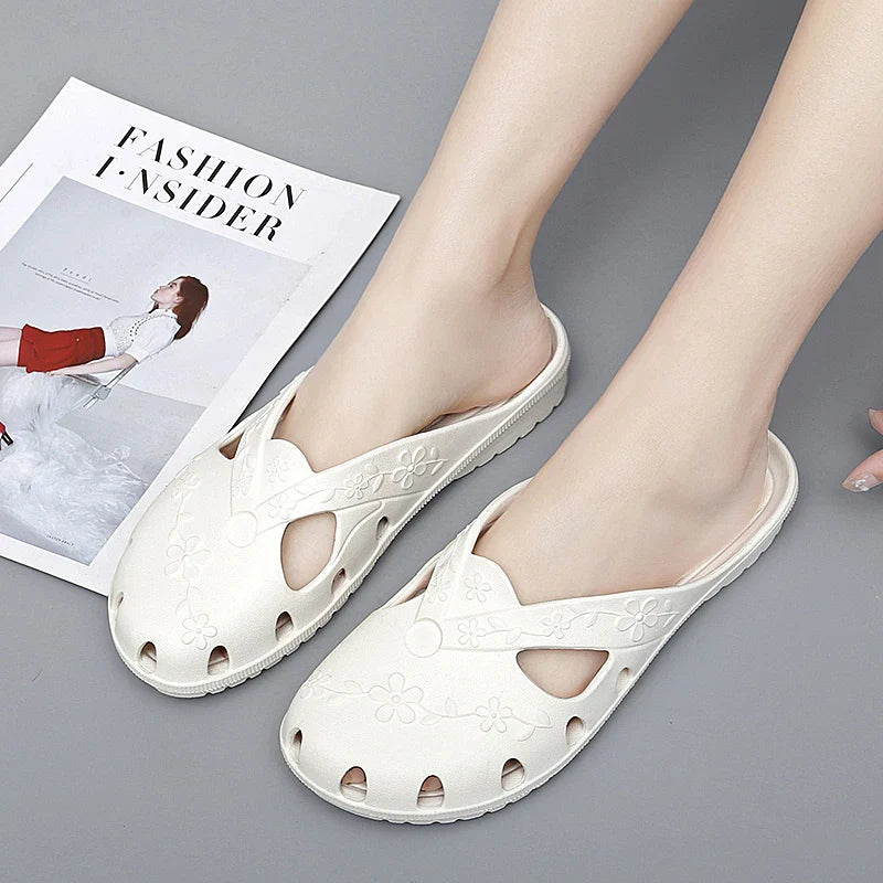 A pair of white, flat, slip-on jelly slippers featuring floral cutouts and patterns.