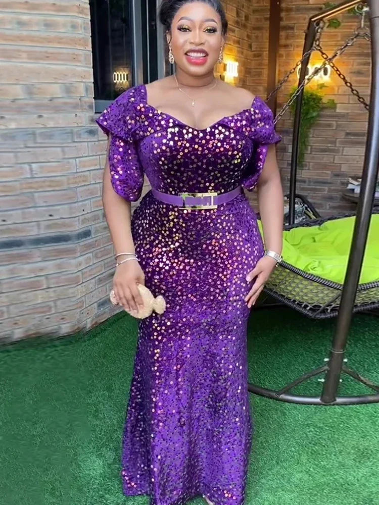 A woman wears a floor-length purple sequin mermaid dress with petal sleeves and a matching belt.