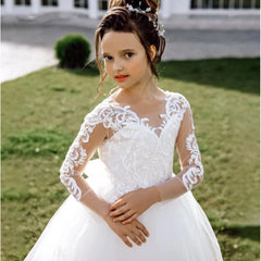 A young girl wears a floor-length white A-line dress with long lace sleeves and floral appliques.