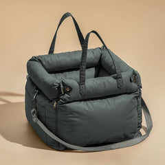 A dark grey, padded pet booster seat with carrying handles and an adjustable shoulder strap.