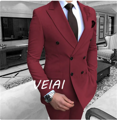 A man wears a burgundy double-breasted suit jacket with a white shirt and dark tie.