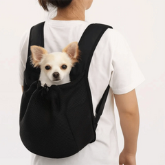 A person wears a black mesh pet backpack with a small white dog peeking out from the top.