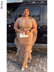A woman wears a beige sleeveless pleated midi dress with ruffled edges and a matching waist tie.