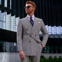 A man wears a double-breasted, glen plaid suit with peak lapels and a patterned tie.