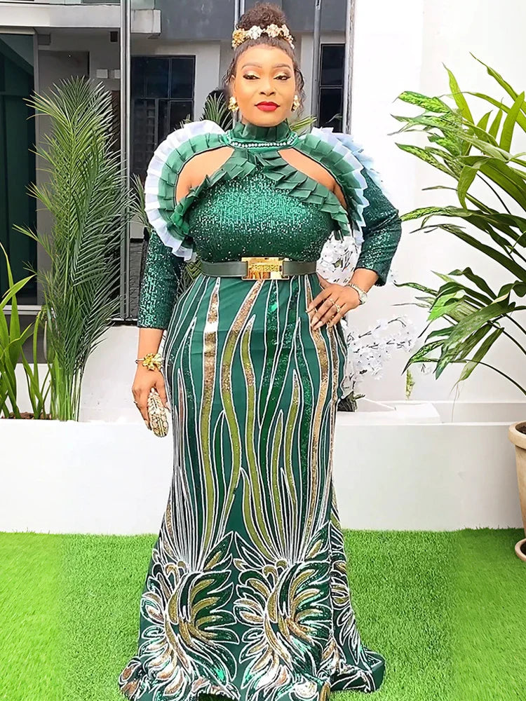 A woman wears a floor-length green sequined African-style gown with puff sleeves and a gold belt.