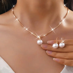 A gold-tone necklace with a single pearl pendant and matching pearl drop earrings.