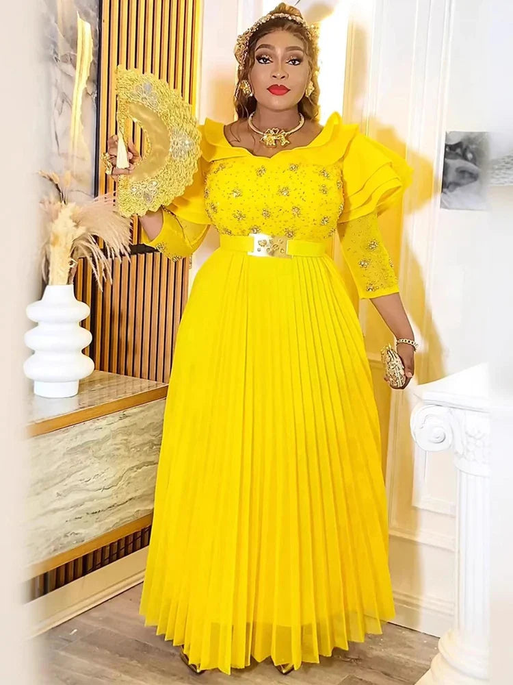 A woman wears a bright yellow floor-length pleated maxi dress with crystal embellishments.