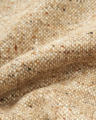 A close-up view of a textured, tan-colored woolen fabric with subtle flecks of brown and black.