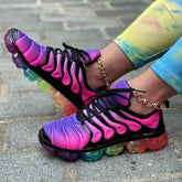 A pair of rainbow-gradient mesh sneakers with black overlays and transparent multicolored soles.