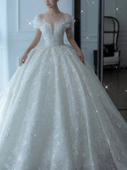 A white floor-length ball gown wedding dress with a beaded sweetheart bodice and short sleeves.