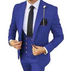 A man wears a slim-fit royal blue three-piece suit with a polka-dot tie and a lapel pin.