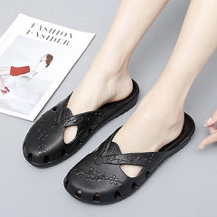 A pair of black slip-on jelly sandals featuring floral embossed details and cut-out sides.