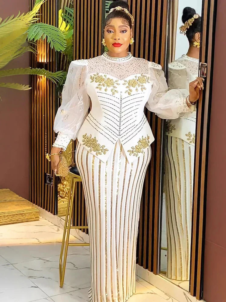 A woman wears a white floor-length gown with gold sequin stripes, puff sleeves, and floral accents.