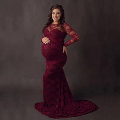 A pregnant woman wears a long-sleeved, wine red lace mermaid maternity gown with a train.