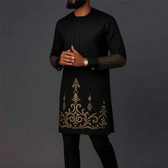 A man wears a black long-sleeve African kaftan set with gold embroidery and patterned cuffs.