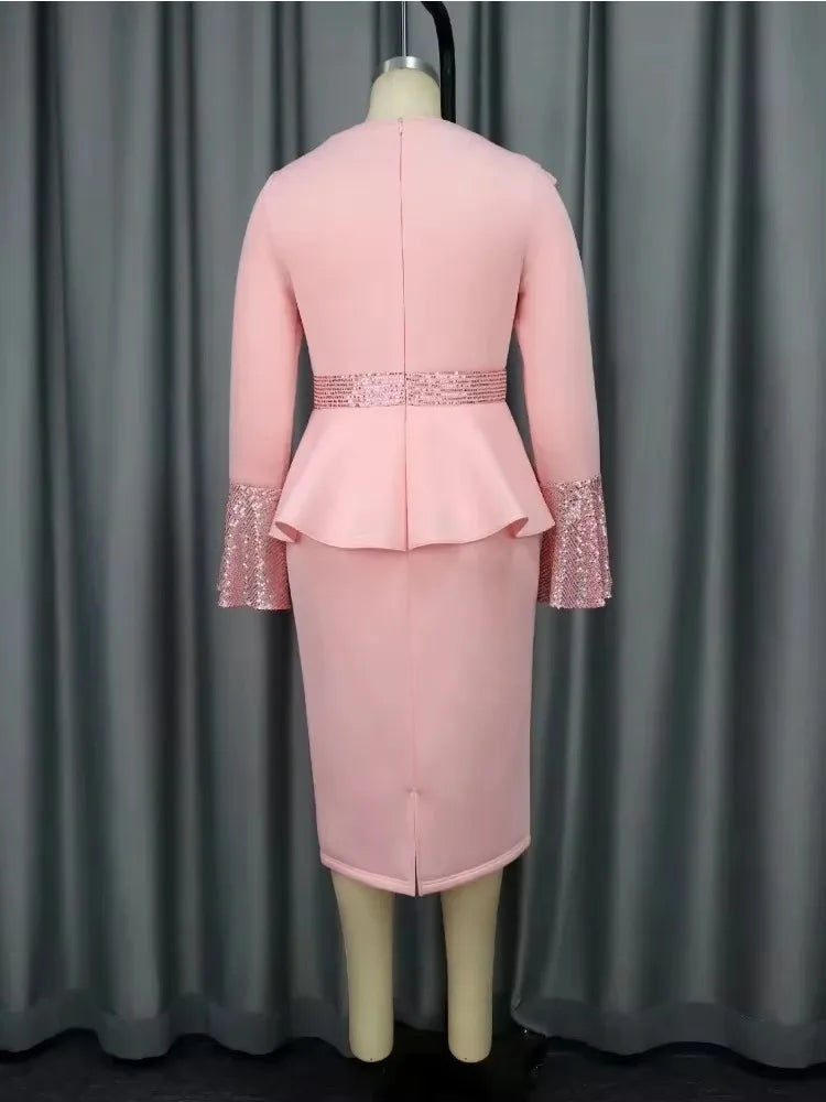 A back view of a pink knee-length sheath dress with long sleeves, sequin cuffs, and a peplum waist.