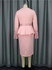 A back view of a pink knee-length sheath dress with long sleeves, sequin cuffs, and a peplum waist.