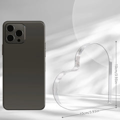 A clear acrylic heart-shaped ornament measuring 10 centimeters wide and tall next to a smartphone.