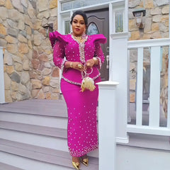 A woman wears a magenta long-sleeved dress with pearl embellishments and ruffled shoulders.