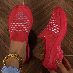 A pair of red slip-on mesh sneakers with a platform sole and white patterned accents.