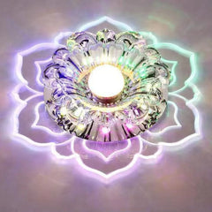 A modern crystal ceiling light shaped like a flower with a central LED bulb and glowing edges.