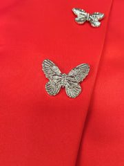 Two silver butterfly-shaped metal embellishments are attached to a vibrant red fabric.