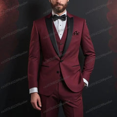 A man wears a three-piece burgundy suit with a black shawl collar, white shirt, and black bow tie.
