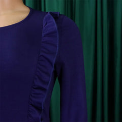 A close-up of a dark purple long-sleeved dress featuring a ruffled detail along the shoulder.
